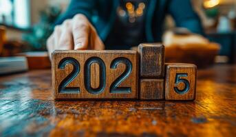 A person is carefully positioning wooden blocks that read 2025 on a rustic table, symbolizing the upcoming year and new beginnings. photo