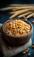 A rustic wooden bowl filled with golden wheat grains rests on burlap, surrounded by stalks of wheat in soft lighting. photo