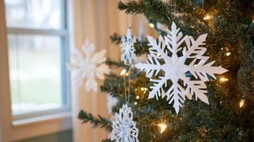 Close-up of a large white snowflake ornament hanging on a decorated Christmas tree photo