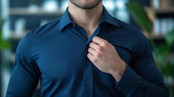A man adjusting the collar of his blue dress shirt. photo