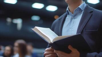 A Man in a Suit Reads a Book While Standing in a Crowd photo
