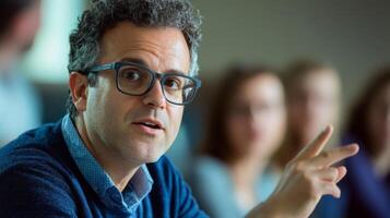 A man wearing glasses gestures with his hand while speaking. photo