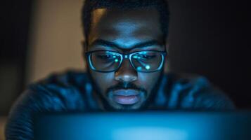 Close-up of a man in glasses looking at a laptop screen photo