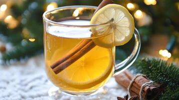 Glass of Lemon and Cinnamon Tea with a Christmas Tree Background photo