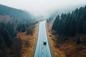 Car travels on an empty road surrounded by misty forests photo