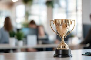 Golden trophy on a desk in a modern office environment with computers in the background photo