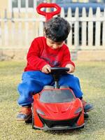 A young boy riding a red toy car photo