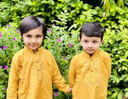 Two boys in yellow shirts standing in front of flowers photo