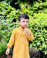 A young boy in a yellow kurta and pants photo