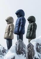 Three people wearing puffy jackets standing on top of a mountain photo