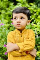 A young boy in yellow standing in front of flowers photo