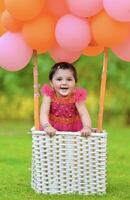 A baby girl in a basket with balloons photo