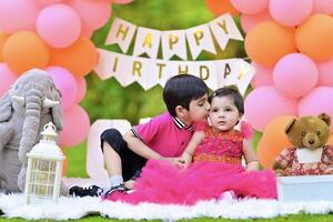 Two children in pink dresses sitting on a blanket with balloons photo