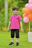 A young boy in pink shirt standing in front of balloons photo
