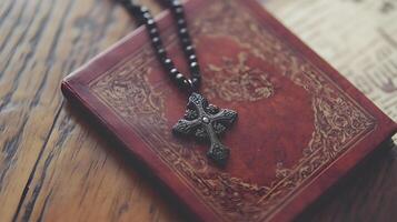 A cross pendant resting on an ancient book atop a rustic wooden surface background with copy space photo