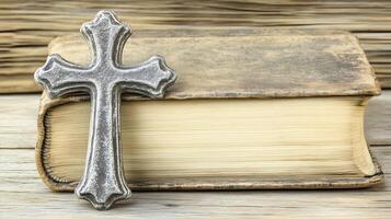 Cross resting on an aged book atop a wooden surface with ample negative space photo