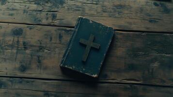 Cross placed on an old book resting on a rustic wooden table with plenty of empty space photo