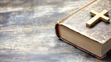 Cross placed on an open book resting on a rustic wooden background with copy space photo