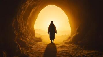 Jesus' resurrection as he emerges from the empty tomb during dawn with a glowing backdrop photo