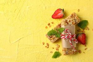 Tasty granola bars on yellow background, top view photo