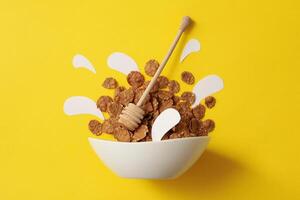 Bowl with muesli and dipper on yellow background photo