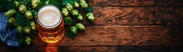 Glass of beer, green hops and checkered plaid on wooden background with space for text photo