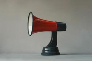 Red and black megaphone standing on a table with a gray background photo