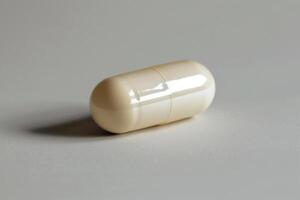 Single beige pill lying on a white surface photo