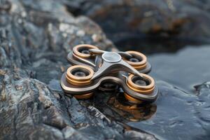 Modern fidget spinner resting on wet rocks by the water photo
