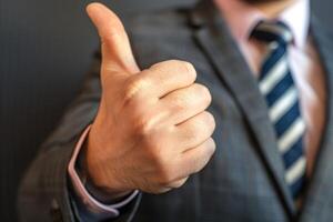 Businessman showing thumb up gesture approving successful business agreement photo