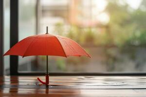 Red umbrella with rain drops on wooden table by window during rainy season photo