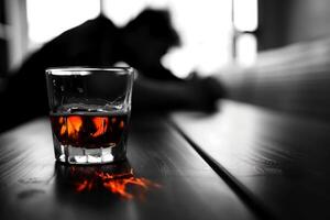 Glass of alcohol with a man passed out in the background photo