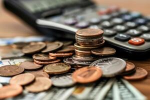 Stack of coins lying on dollar banknotes with calculator in the background photo