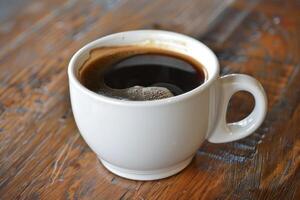 Steaming cup of black coffee sitting on rustic wooden table photo