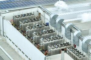 Sustainable industrial rooftop. Aerial view showcasing solar panels, ventilation systems, and industrial chillers. Renewable energy and efficient cooling in modern manufacturing facilities. photo