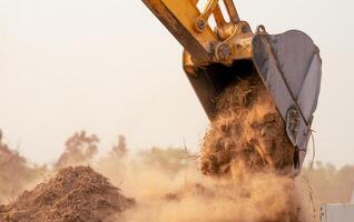 Backhoe working by digging soil at construction site bucket of crawler excavator breaking ground for new development project earth moving machine in action. Foundation work on construction project. photo