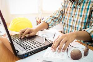 A man working on a laptop computer with a calculator photo