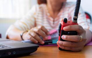 Female radio operator using Walkie - Talkie to communicate with other people and working with document on working desk, Communication concept. photo