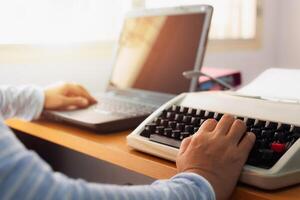 Woman typing both typewriter and laptop on working desk in office. photo