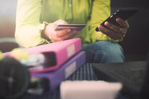Woman in casual shirt using mobile smartphone paying with credit card online while making orders via the Internet. photo