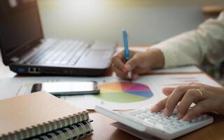 A person using a calculator and pen on a desk photo