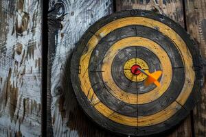 Orange dart hitting the center of an old target on a wooden background photo
