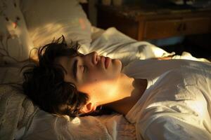 Young man sleeping peacefully in bed while sun is shining through window photo