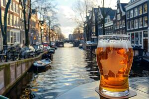 Glass of beer standing on table with canal and typical houses in amsterdam in background photo