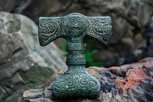 Ancient stone axe head with carvings resting on rock photo