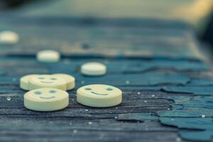 Smiley face pills resting on a wooden surface photo