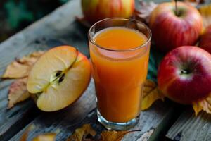 Glass of apple juice with fresh apples on wooden table surrounded by autumn leaves photo