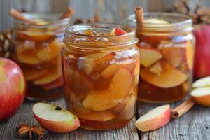 Apple compote with cinnamon sticks is standing on a wooden table photo