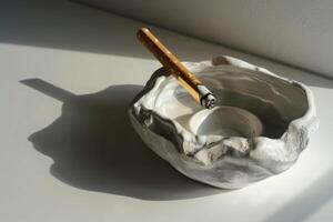 Smoldering cigarette resting on a ceramic ashtray casting a shadow photo
