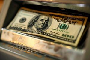 Stack of one hundred dollar bills being withdrawn from atm photo